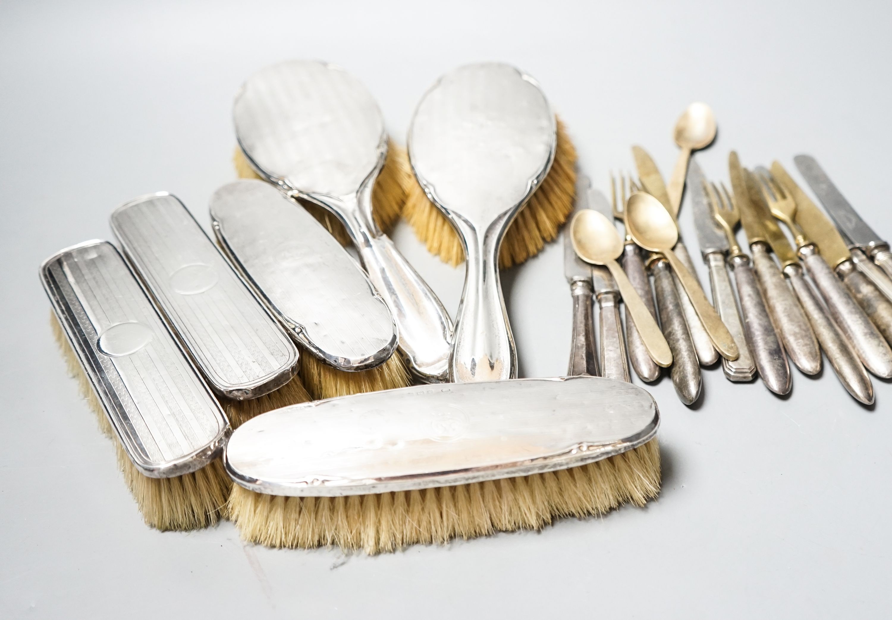 Six assorted silver mounted clothes and hair brushes and a small group of sterling handled cutlery.